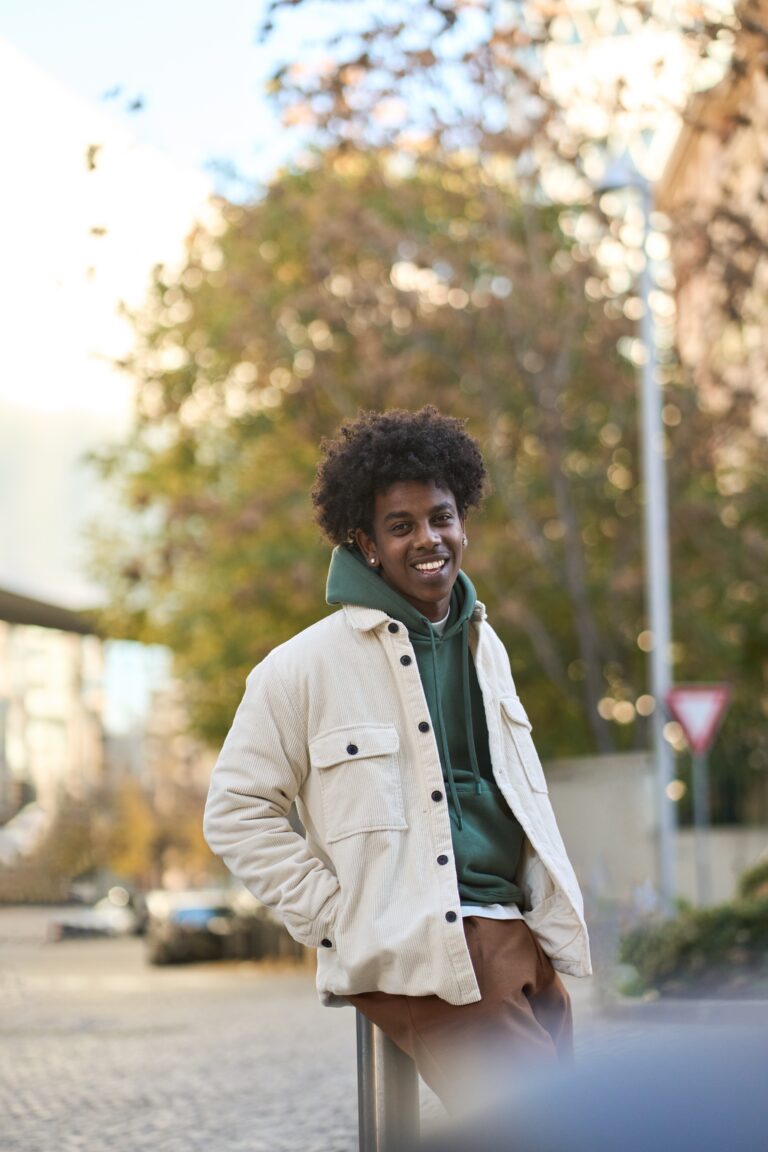 Happy young African American man smiling while standing confidently in front of a large object or structure.